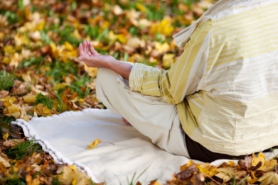 21246789 - rear view of senior woman meditating in lotus position at park